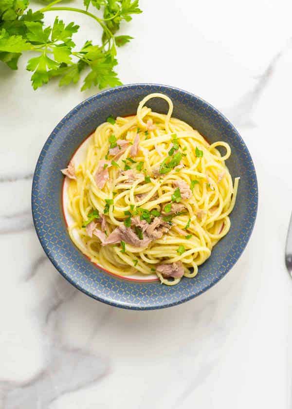 blue bowl with pasta and tuna and cilantro on the side