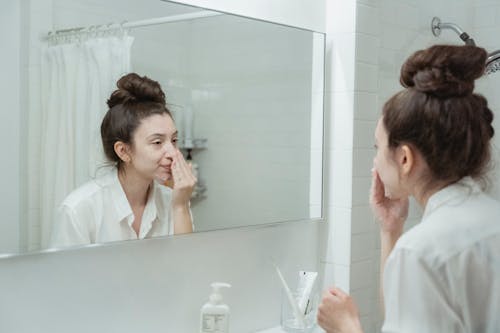 Free Woman in a White Bathroom Washing Face and Looking Mirror Stock Photo