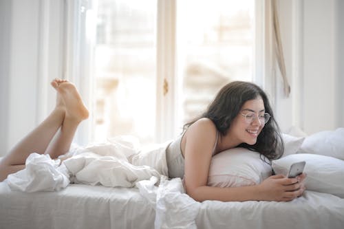 Free Woman in Tank Top Lying on Bed Stock Photo