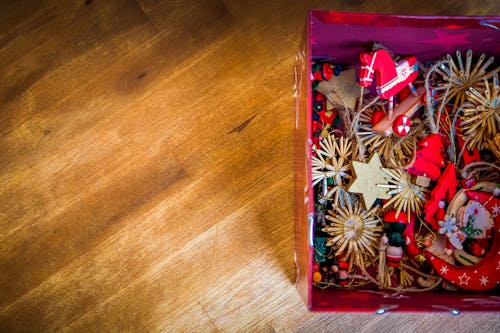 Free Bright and colorful handmade Christmas ornaments in a box on a wooden desk, perfect for holiday decor. Stock Photo