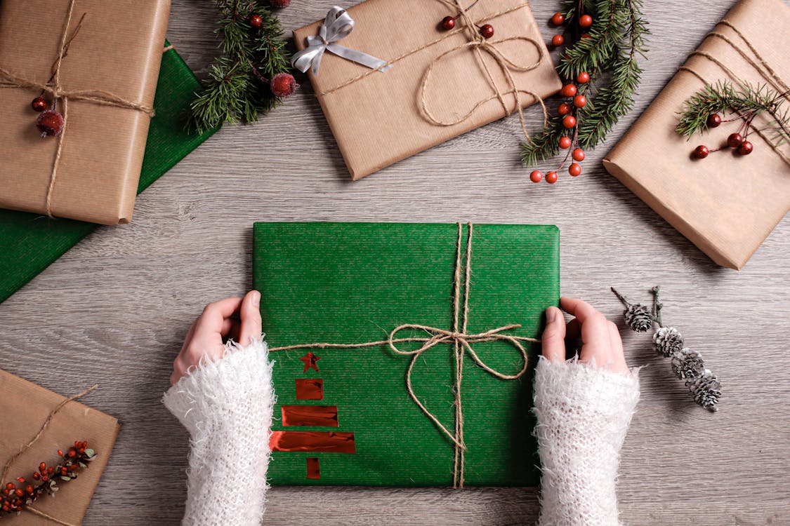 Free Top view of Christmas gifts wrapped in green and brown paper with festive decor. Stock Photo