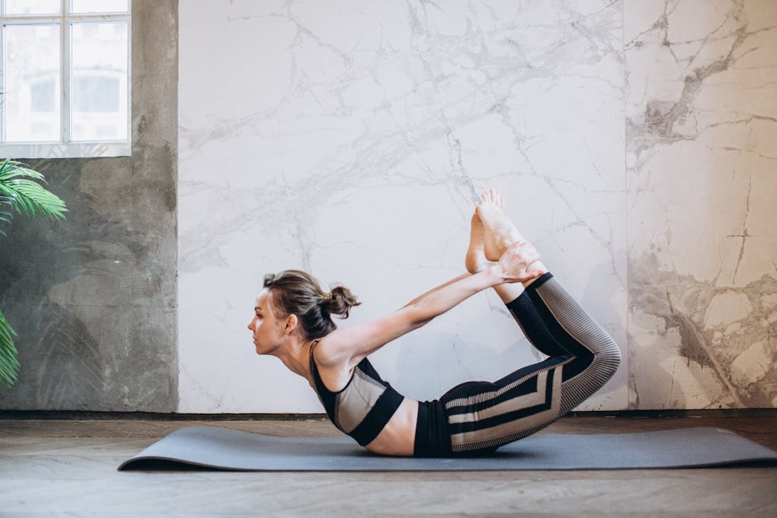 Free A woman performing the bow pose in a serene indoor setting, emphasizing fitness and mindfulness. Stock Photo