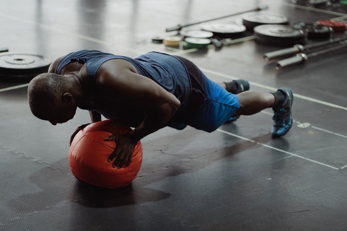 Free Adult man in gym doing push-up on a medicine ball, demonstrating strength and balance. Stock Photo