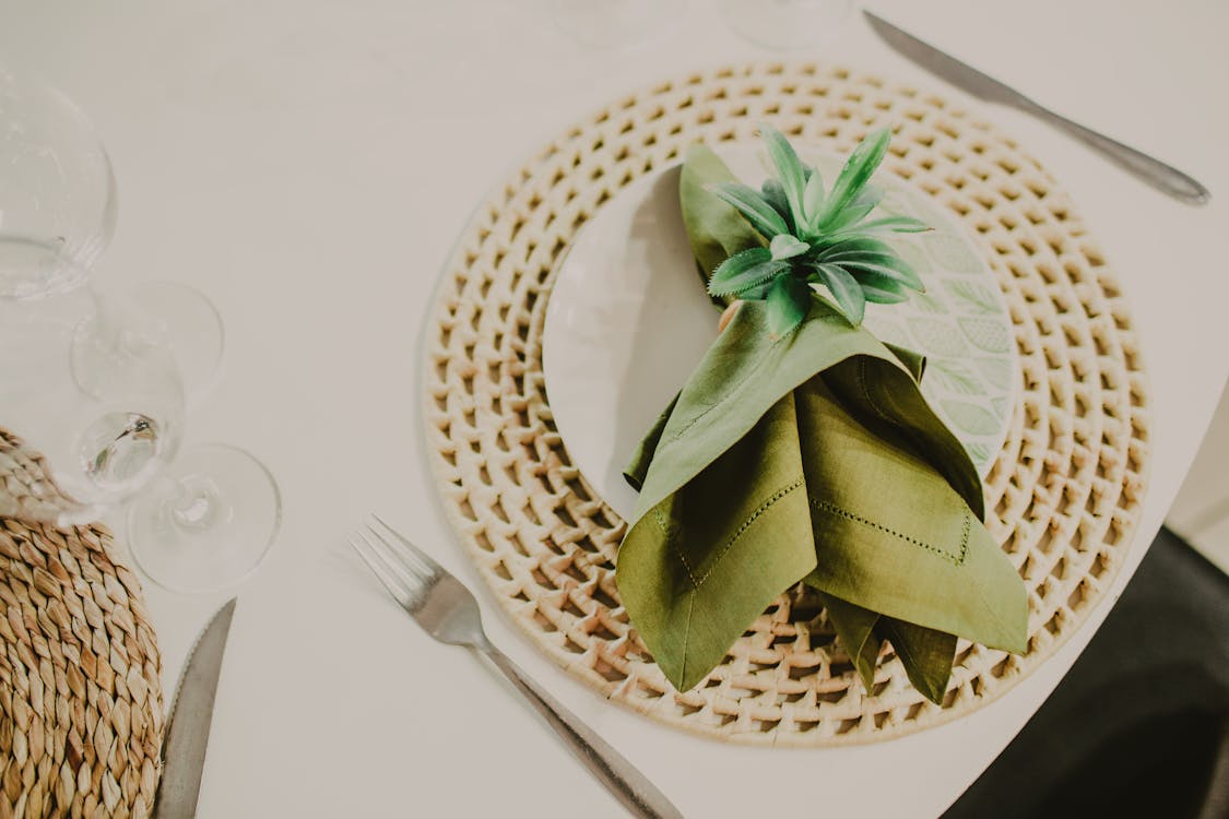 Free Chic table setting with woven mat, green napkin, and cutlery for a sophisticated dining experience. Stock Photo