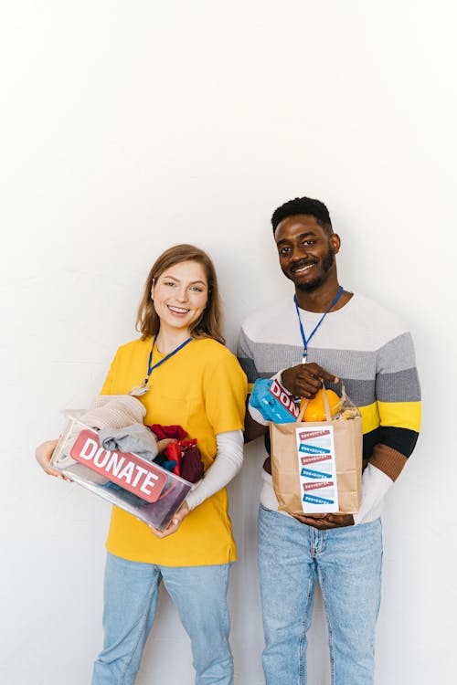 Free Smiling volunteers holding donation boxes against white background. Stock Photo