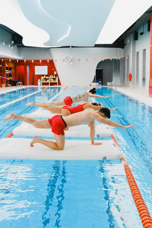 Free Group of people exercising on floats in an indoor swimming pool, performing stretches and balance exercises. Stock Photo