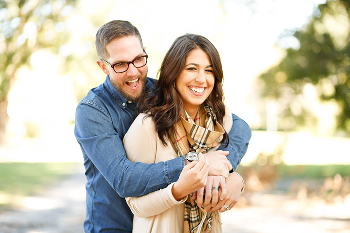 Happy couple embracing outdoors, representing family tension over dating wealthier partners.