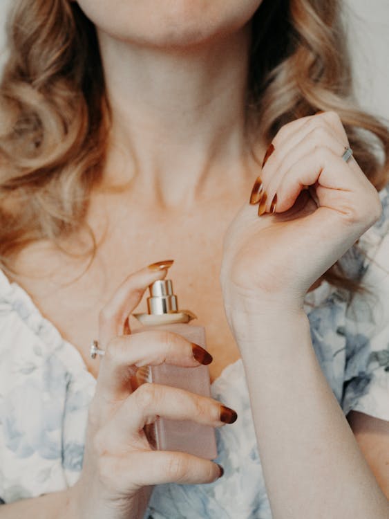 Free Close-up of a woman spraying perfume on her wrist, showcasing elegance and femininity. Stock Photo