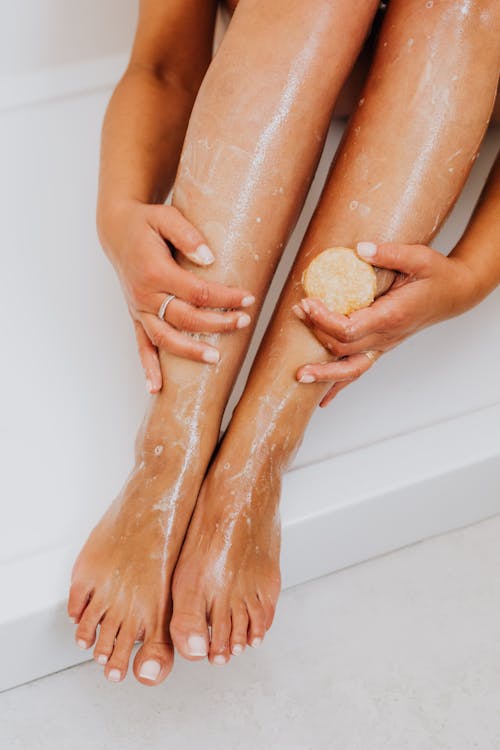 Free Close-up of a woman's legs being exfoliated with soap, showcasing skincare routine. Stock Photo