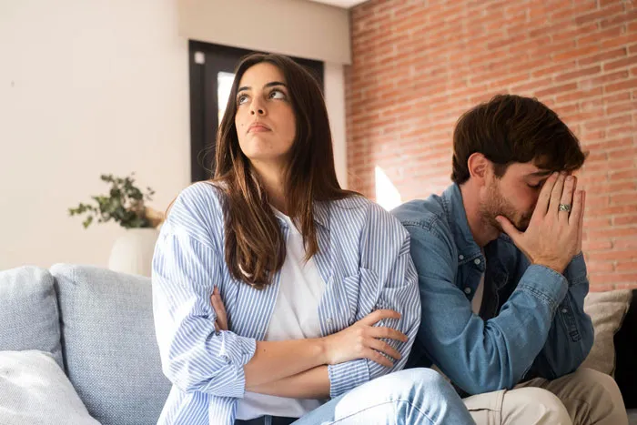 Woman locks out affair partner's kid in winter, sitting upset with man on couch during tense moment at home.