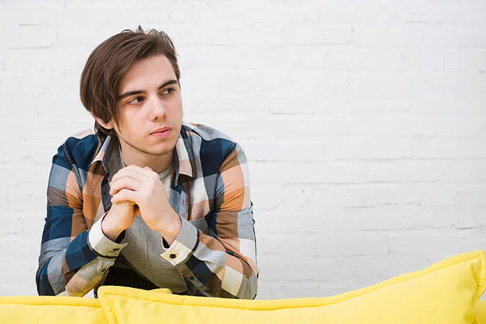 Young man in a plaid shirt looking thoughtful, representing challenges with a dad turned trans demanding kids call him mom.