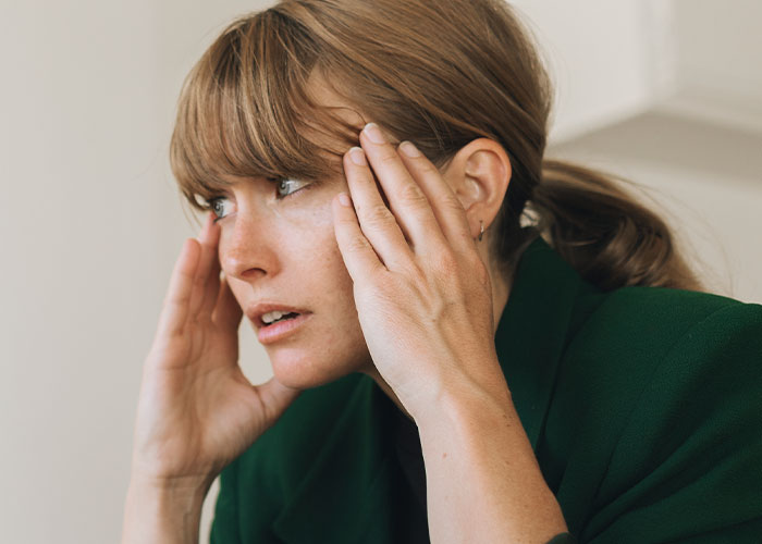 Worried woman holding her head, reacting to dad upset about daughter’s home and saying something weird.