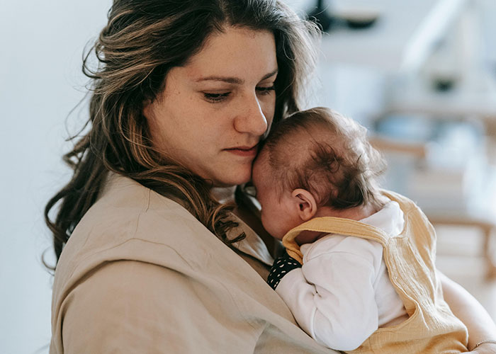 Woman holding a baby closely, reflecting on a serious situation involving illegal baby adoption and CPS intervention.