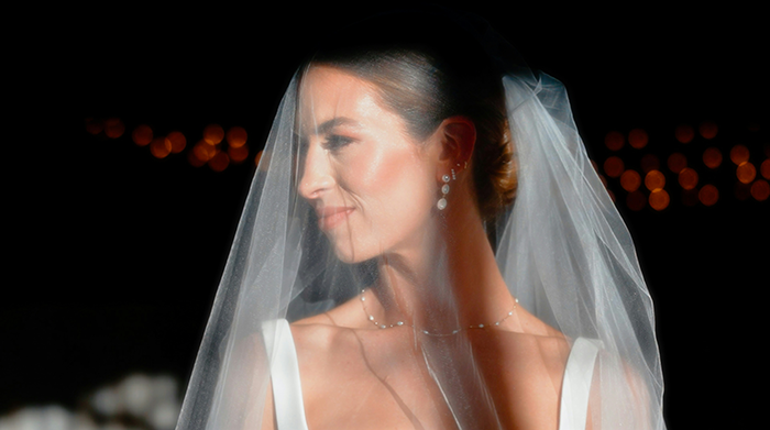 Bride in wedding dress and veil looking sideways with calm expression during a ceremony, capturing couple split at altar moment.