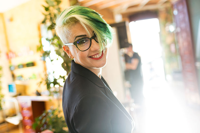 Woman with green and blonde hair smiles confidently, showcasing her bold style change despite partner’s disapproval.